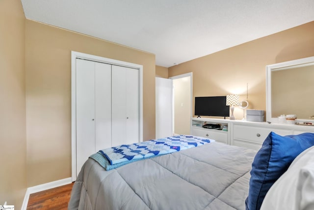 bedroom with wood finished floors, baseboards, and a closet