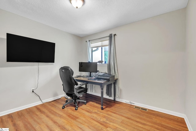 office featuring a textured ceiling, visible vents, wood finished floors, and baseboards