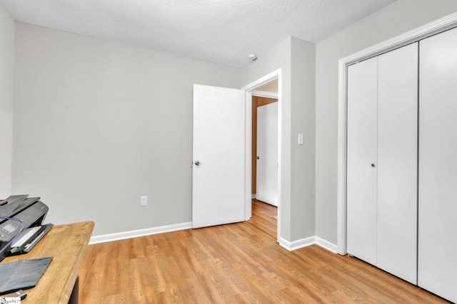office with light wood finished floors, a textured ceiling, and baseboards