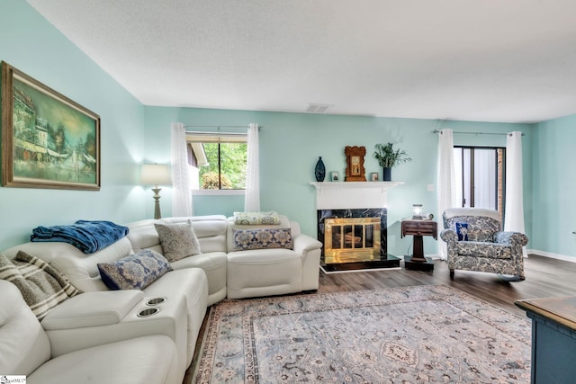 living area featuring visible vents, wood finished floors, a premium fireplace, and a textured ceiling