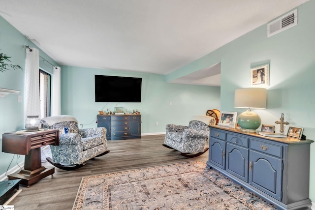 living room with baseboards, visible vents, and wood finished floors