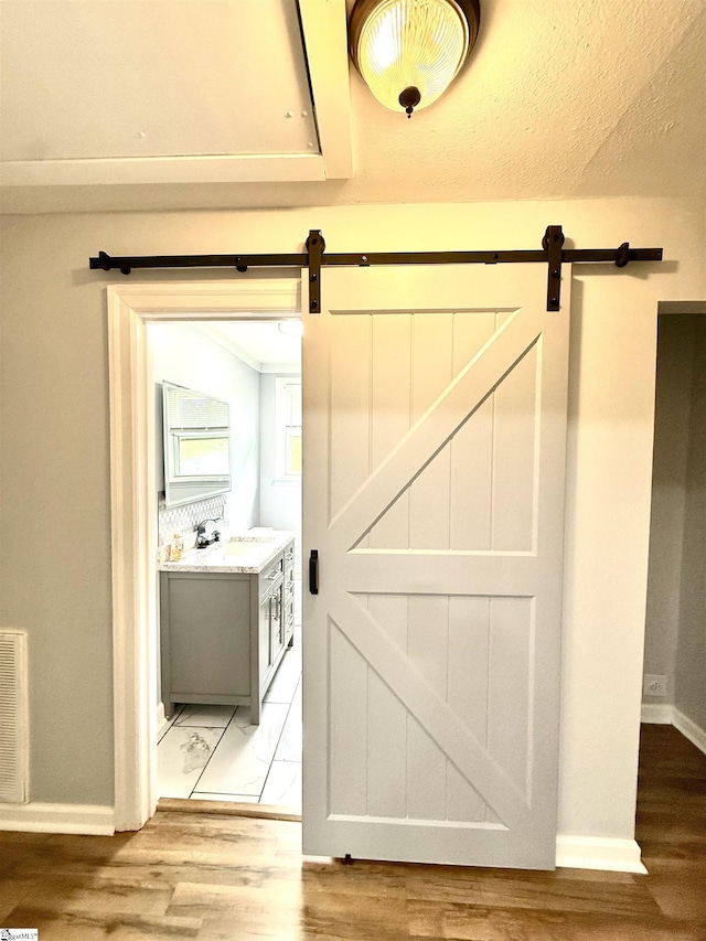 interior space with baseboards, a barn door, wood finished floors, and a sink