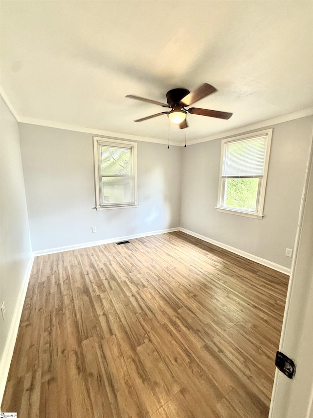spare room with wood finished floors, a healthy amount of sunlight, and ornamental molding