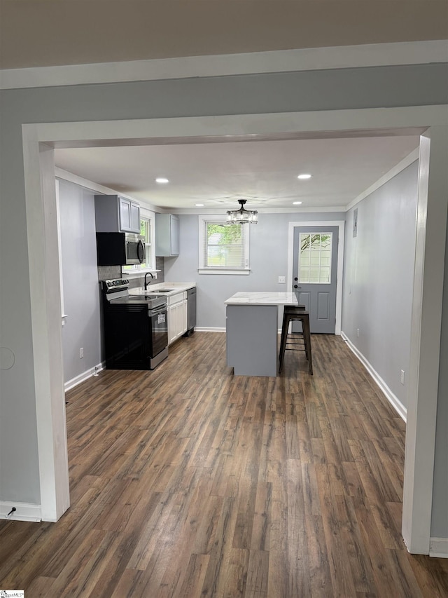 kitchen with dark wood finished floors, stainless steel appliances, light countertops, a sink, and baseboards