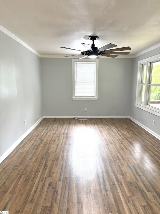 spare room with baseboards, ornamental molding, ceiling fan, and dark wood-type flooring