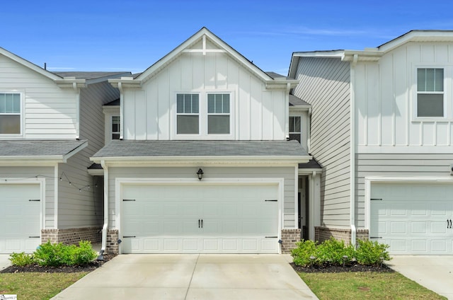 multi unit property featuring a garage, brick siding, board and batten siding, and driveway