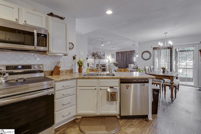 3 Heatherfield Dr, Simpsonville, SC 29680 - kitchen featuring a sink, light wood-style floors, backsplash, a peninsula, and appliances with stainless steel finishes