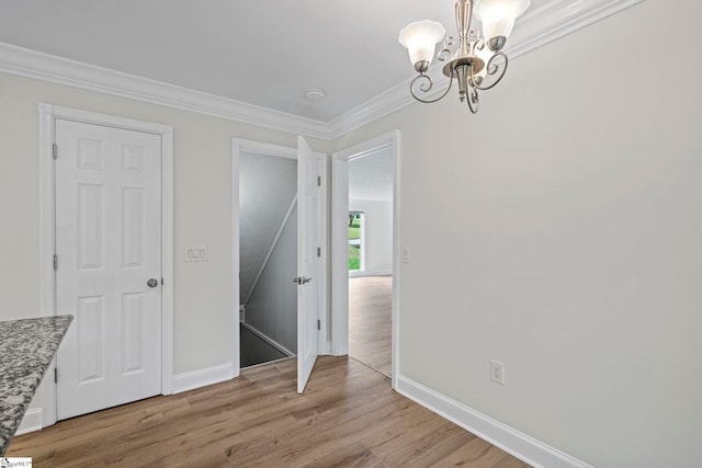 unfurnished dining area with light wood finished floors, a chandelier, ornamental molding, and baseboards
