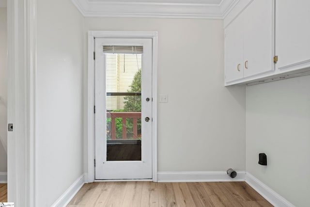 clothes washing area with ornamental molding, cabinet space, baseboards, and light wood-style floors