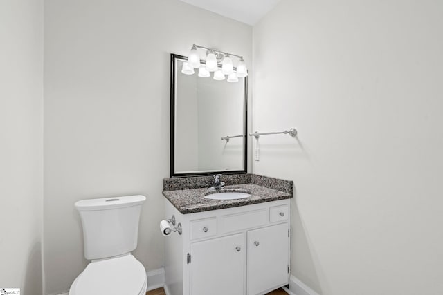 bathroom with baseboards, toilet, and vanity