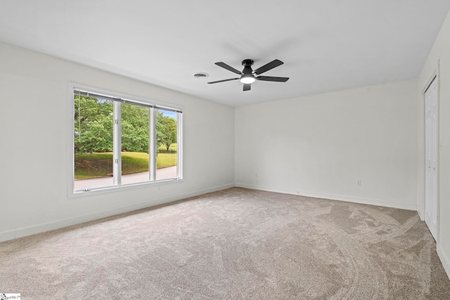 carpeted empty room featuring ceiling fan, visible vents, and baseboards