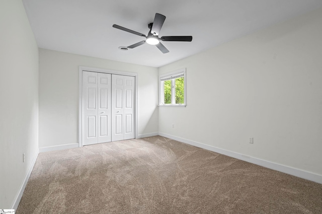 unfurnished bedroom with a closet, ceiling fan, carpet floors, and baseboards