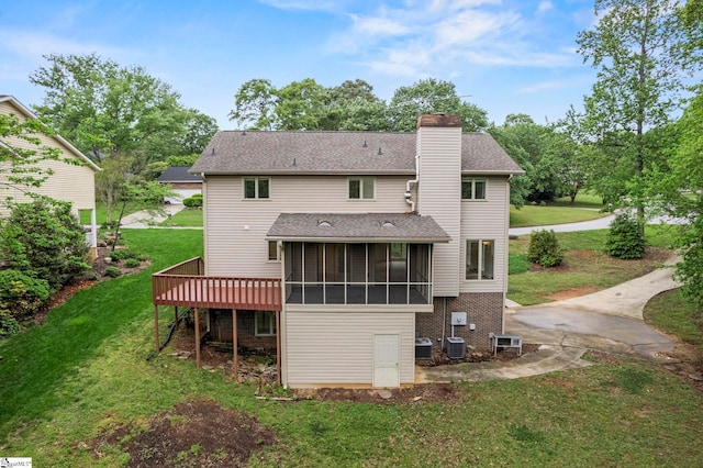 back of house with a chimney, a yard, a shingled roof, a wooden deck, and a sunroom