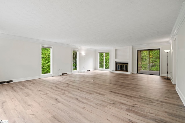 unfurnished living room with wood finished floors, visible vents, a healthy amount of sunlight, and crown molding