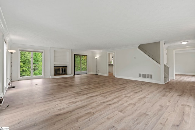 unfurnished living room with light wood finished floors, visible vents, and ornamental molding
