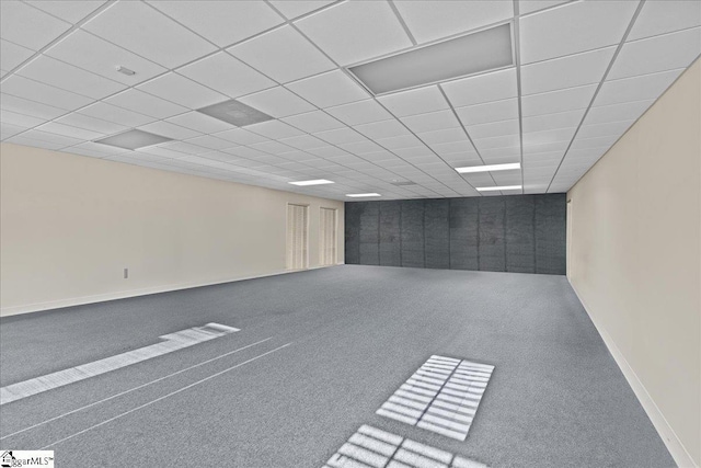 basement featuring baseboards, carpet flooring, and a paneled ceiling