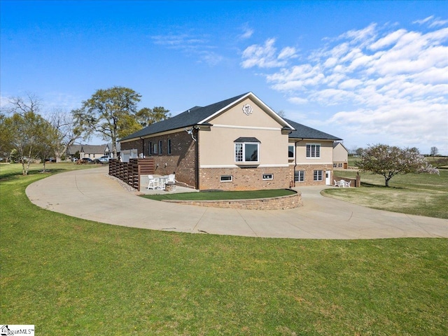 view of front of house featuring brick siding, a front lawn, and curved driveway