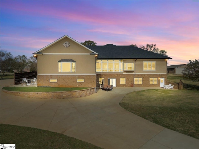 view of front of house with stucco siding, a front yard, a patio, and brick siding