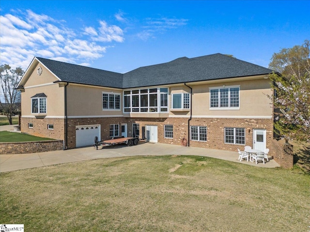 rear view of property featuring driveway, a yard, a patio, and brick siding