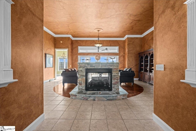 living area featuring baseboards, a stone fireplace, and crown molding