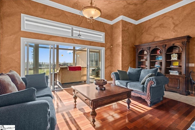 living room featuring hardwood / wood-style flooring, ornamental molding, a textured wall, and a towering ceiling