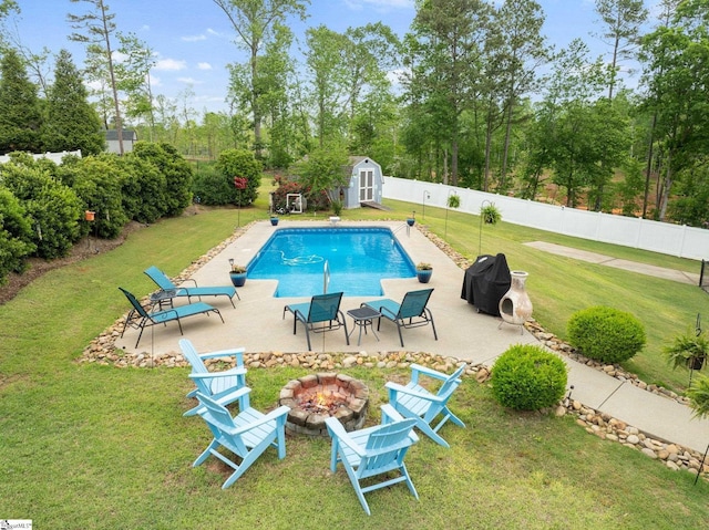 view of pool with a lawn, a fire pit, and a shed