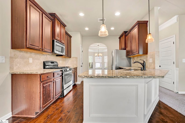 kitchen with light stone counters, a sink, stainless steel appliances, arched walkways, and a peninsula