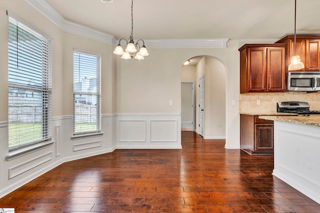 kitchen featuring arched walkways, a healthy amount of sunlight, appliances with stainless steel finishes, and light stone counters