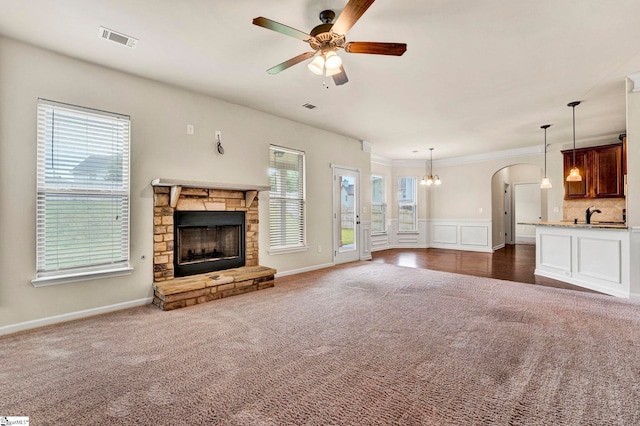 unfurnished living room with visible vents, dark colored carpet, a ceiling fan, and a fireplace