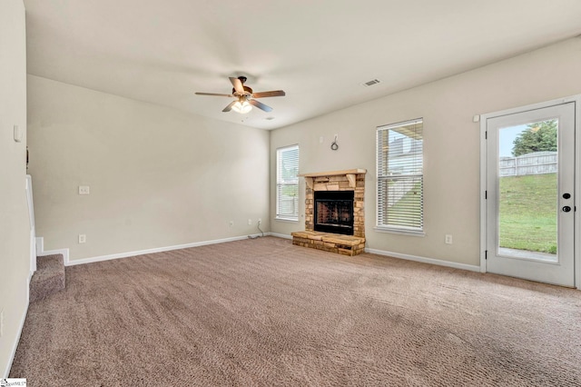 unfurnished living room with carpet flooring, visible vents, baseboards, a fireplace, and a ceiling fan