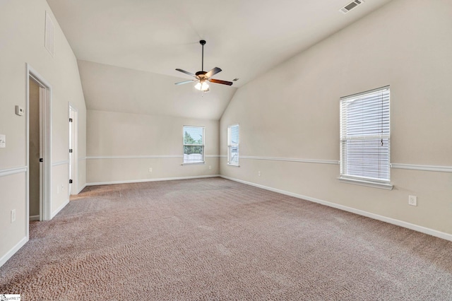 empty room featuring lofted ceiling, visible vents, baseboards, carpet floors, and a ceiling fan