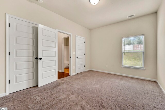 unfurnished bedroom with visible vents, carpet floors, and baseboards