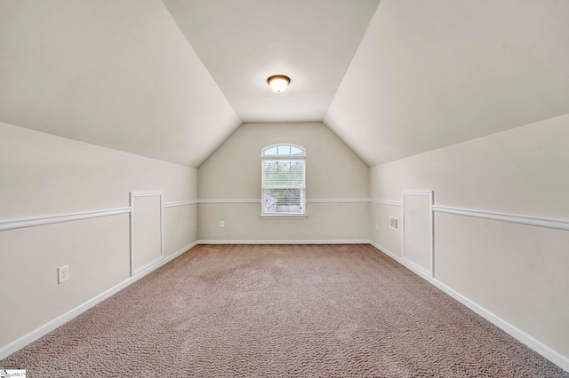 additional living space with baseboards, vaulted ceiling, and carpet floors