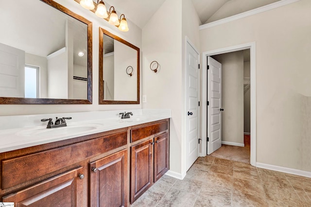 full bath featuring double vanity, a sink, vaulted ceiling, and baseboards
