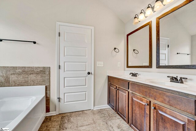 full bath featuring vaulted ceiling, a garden tub, double vanity, and a sink