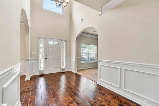 foyer featuring hardwood / wood-style floors, arched walkways, and a wainscoted wall