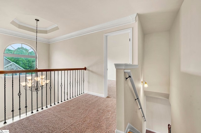 corridor with an upstairs landing, a raised ceiling, baseboards, ornamental molding, and carpet floors