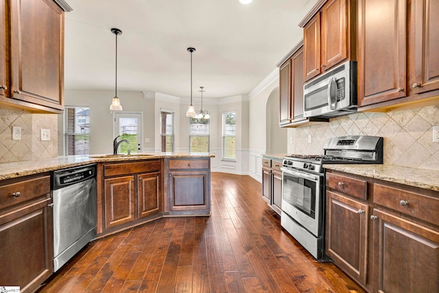 kitchen featuring a sink, appliances with stainless steel finishes, light stone countertops, ornamental molding, and dark wood finished floors