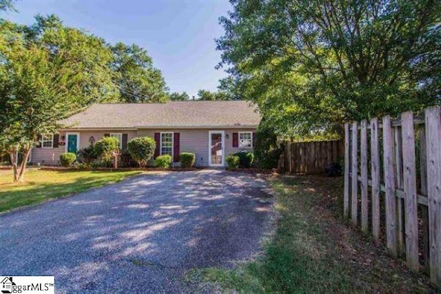 ranch-style home featuring fence and a front lawn