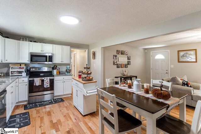 411 Granada Dr, Spartanburg, SC 29303 - kitchen with white cabinetry, a textured ceiling, light wood-style floors, and appliances with stainless steel finishes