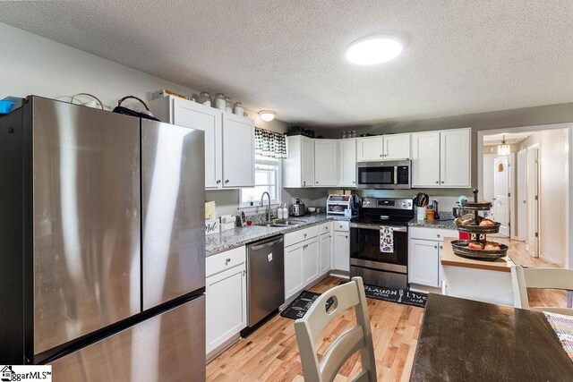 411 Granada Dr, Spartanburg, SC 29303 - kitchen featuring a textured ceiling, white cabinetry, a sink, appliances with stainless steel finishes, and light wood-style floors