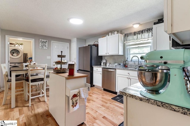 411 Granada Dr, Spartanburg, SC 29303 - kitchen with stainless steel appliances, light wood-style floors, a sink, stacked washer and clothes dryer, and a textured ceiling