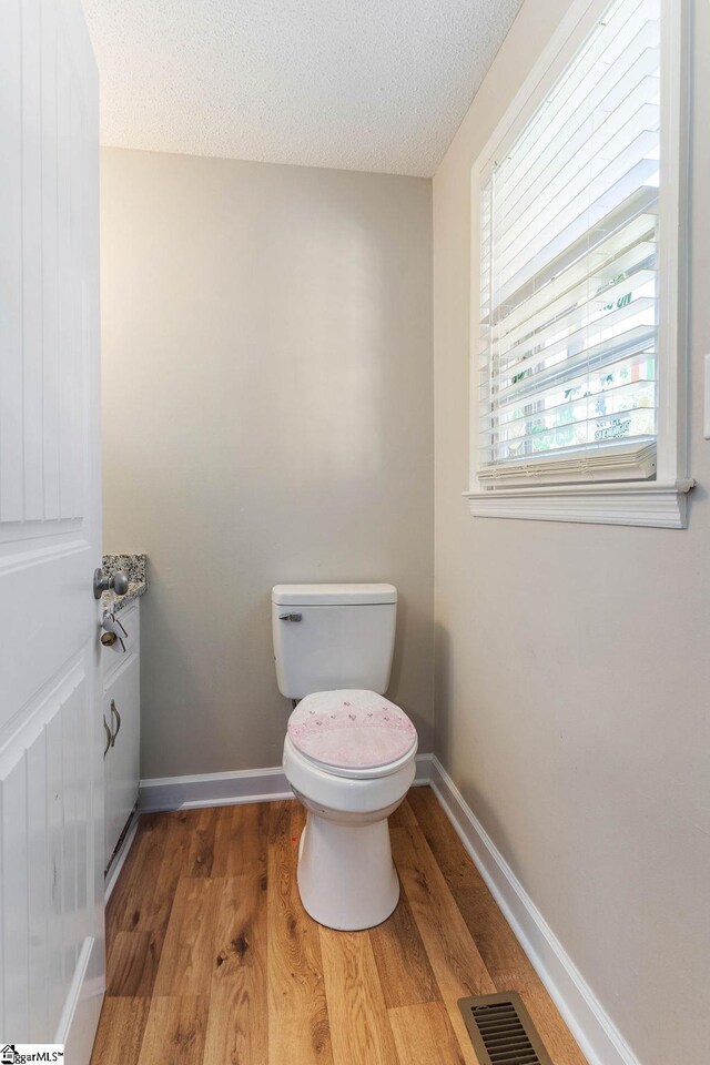 411 Granada Dr, Spartanburg, SC 29303 - bathroom featuring wood finished floors, toilet, baseboards, visible vents, and a textured ceiling