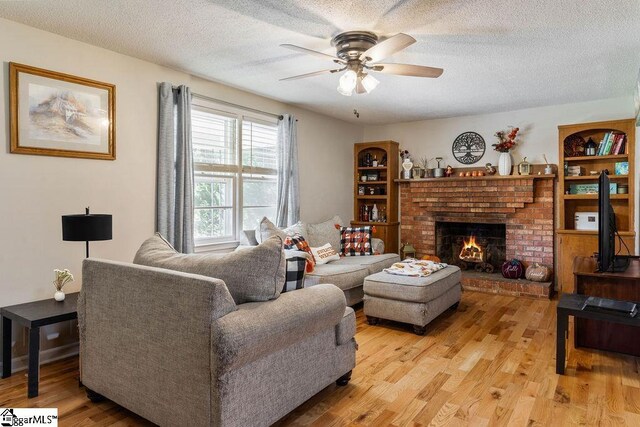 411 Granada Dr, Spartanburg, SC 29303 - living area featuring a brick fireplace, a textured ceiling, ceiling fan, and light wood-style floors