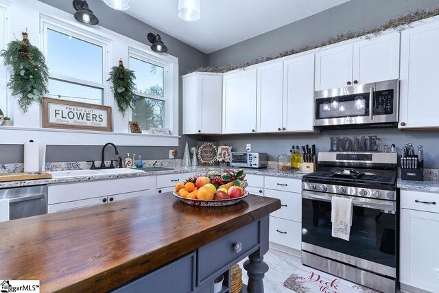 15 S Greenwood Ave, Ware Shoals, SC 29629 - kitchen featuring white cabinetry, a sink, stainless steel appliances, a toaster, and butcher block countertops