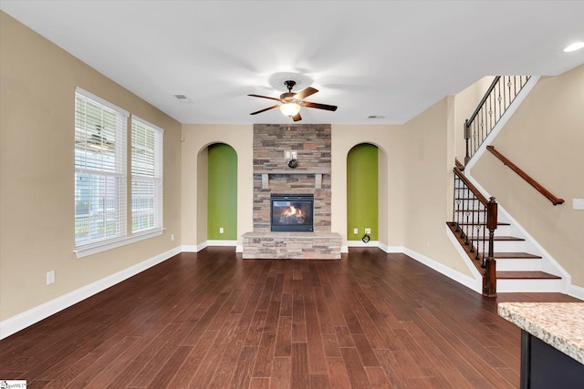unfurnished living room featuring visible vents, arched walkways, a ceiling fan, and a fireplace