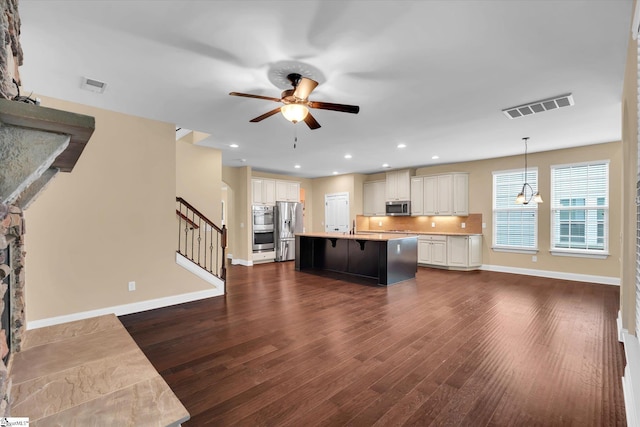 kitchen with dark wood-type flooring, visible vents, stainless steel appliances, and a ceiling fan