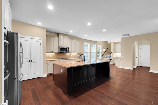 kitchen with light stone counters, visible vents, appliances with stainless steel finishes, and dark wood-style flooring