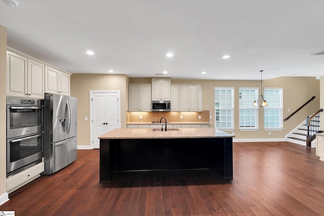 kitchen with light stone countertops, decorative backsplash, stainless steel appliances, a sink, and baseboards