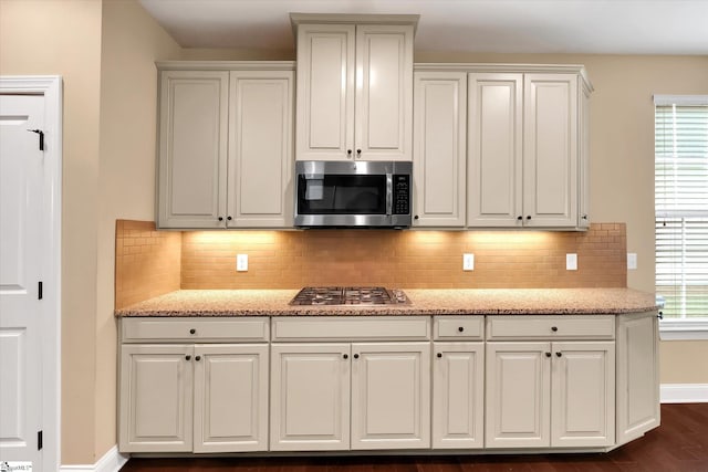 kitchen featuring light stone countertops, appliances with stainless steel finishes, decorative backsplash, and baseboards